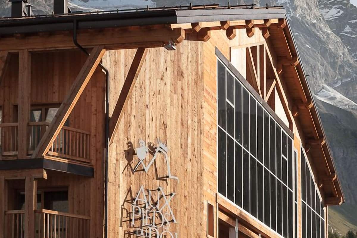 Ein hölzernes Gebäude mit Balkonen und großen Fenstern, mit der Aufschrift