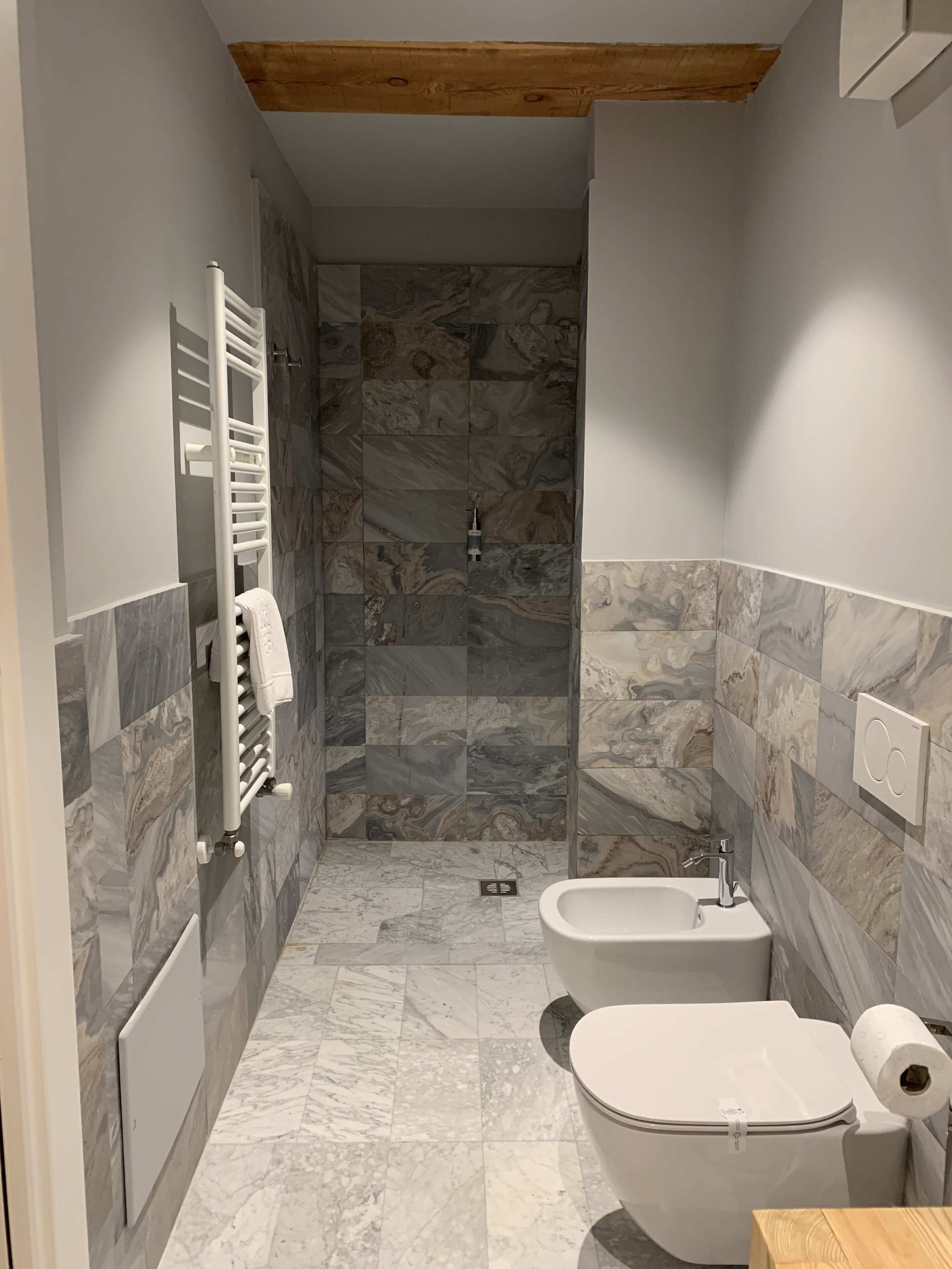 A modern bathroom with a shower, toilet, bidet, and a towel rack.