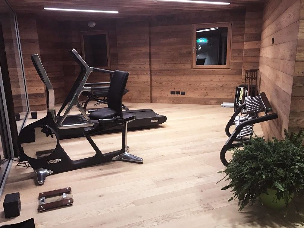 Una palestra con attrezzature per esercizi, pareti in legno e una finestra.