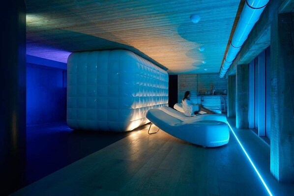 Ein moderner Spa-Raum mit einer großzügigen, gepolsterten Sitzgruppe und einer Holzbeschichtung an der Decke.
