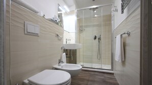 Un baño moderno con inodoro, bidé y ducha con mampara de vidrio.