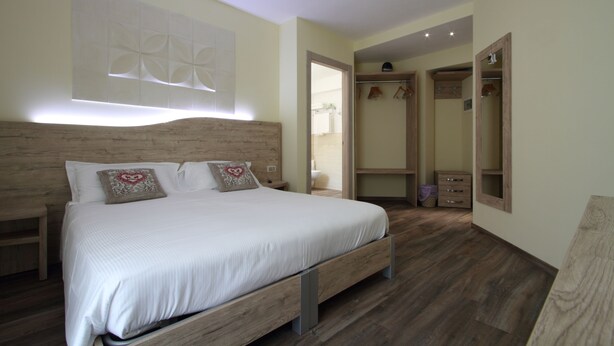 Un dormitorio con una cama de madera, un vestidor y un espejo.