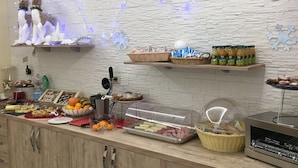 Montaje de bufé con diferentes opciones de comida, una máquina de café y figuras decorativas de renos.