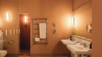 A bathroom with two sinks, a towel rack, a mirror, and a toilet.