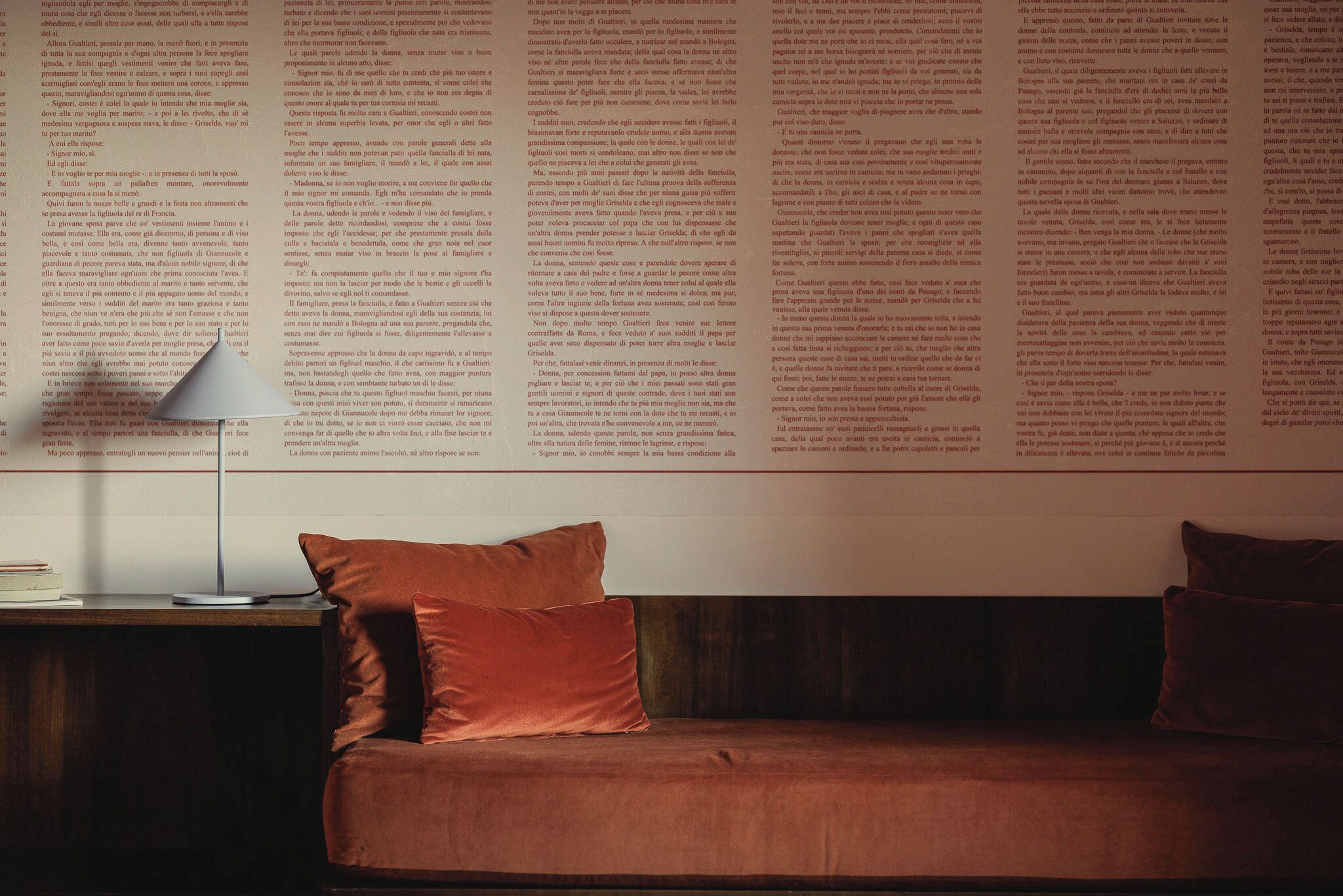 A room with a bed, a nightstand, a lamp, and a wall with text.