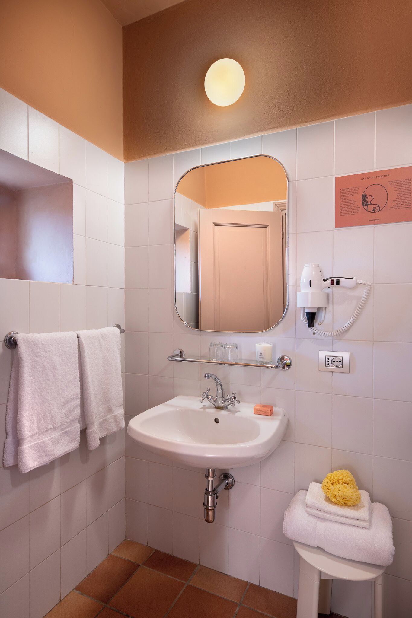A bathroom with a white sink, a mirror, a hairdryer, and a towel rack.