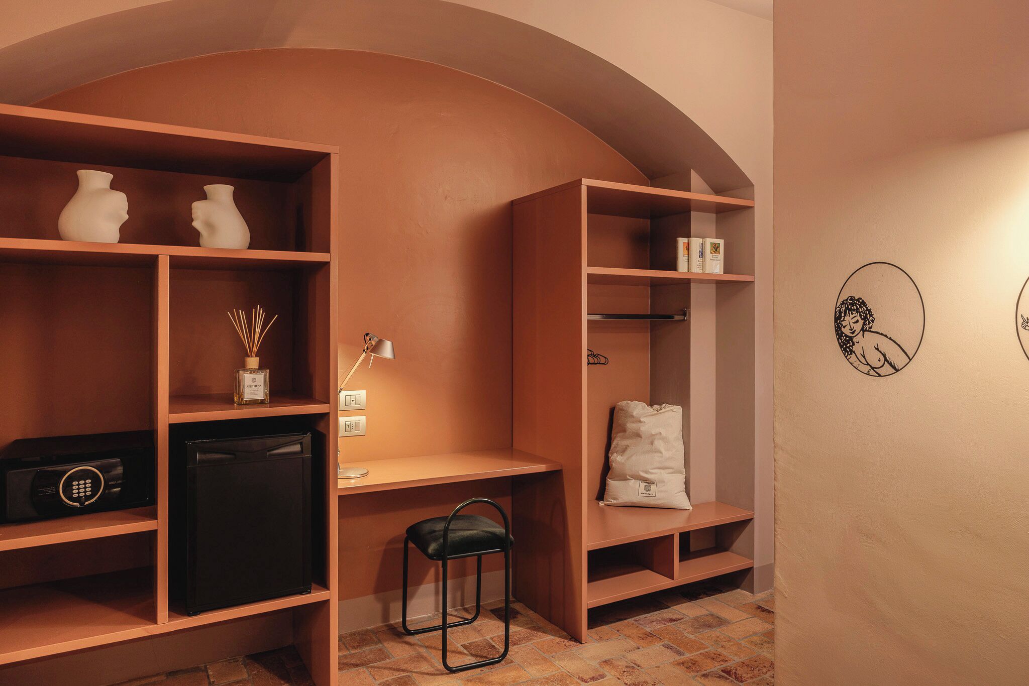 A room with a desk, shelves, a chair, and a small refrigerator.