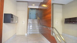 A modern interior with a marble staircase, wooden paneling, and a metal railing. - Pensión Urkia (San Sebastián)