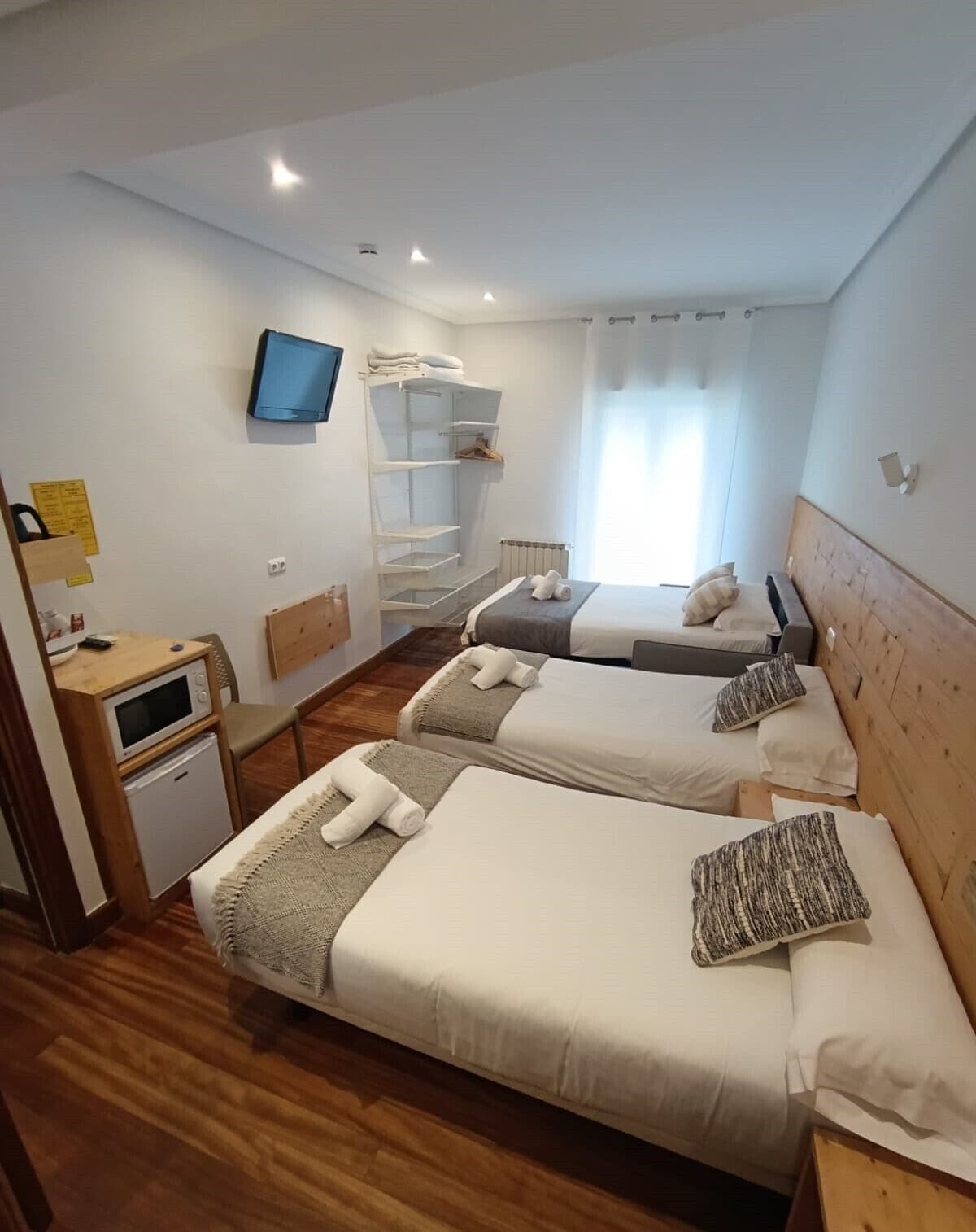 Une chambre d’hôtel avec deux lits, une petite kitchenette, un téléviseur et une armoire intégrée.