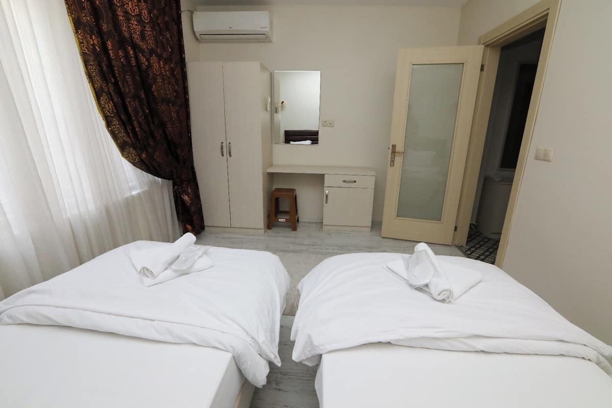 A hotel room with two beds, a desk, a mirror, and a wardrobe.