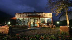 Een modern gebouw met een glazen gevel en een houten terras.