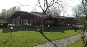 A modern building with a large glass facade, a well-maintained lawn, and a stone pathway. - Hotel Il Ciliegio (Santo Stefano del Sole)
