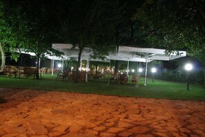 An outdoor seating area with tables and chairs under a canopy, surrounded by trees. - Hotel Il Ciliegio (Santo Stefano del Sole)
