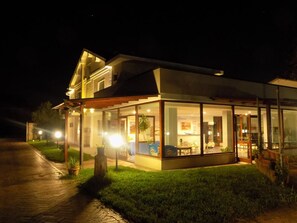 A modern house with a glass-enclosed porch, a paved driveway, and a well-maintained lawn. - Hotel Il Ciliegio (Santo Stefano del Sole)