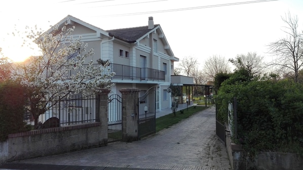 A two-story house with a balcony, a gated driveway, and a garden. - Hotel Il Ciliegio (Santo Stefano del Sole)