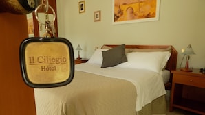 Een hotelkamer met een bed, nachtkastje, lamp en een schilderij aan de muur.