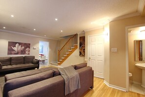 A living room with a sofa set, a staircase, and a bathroom with a sink and toilet. - Pelicanstay in Churchill Meadows (Mississauga)
