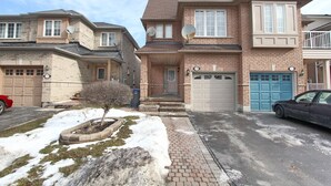 Un quartier résidentiel avec des maisons en briques, une allée et une pelouse recouverte de neige.
