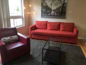 A living room with a red sofa, a red armchair, and a glass coffee table. - Pelicanstay in Churchill Meadows (Mississauga)