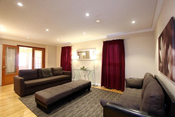A living room with a sofa, ottoman, and a glass coffee table. - Pelicanstay in Churchill Meadows (Mississauga)