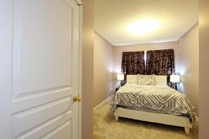 A bedroom with a bed, two bedside lamps, and a door. - Pelicanstay in Churchill Meadows (Mississauga)