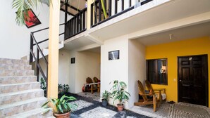 A multi-level building with a staircase, potted plants, and outdoor seating. - Papaya'S Lodge (Tamanique)