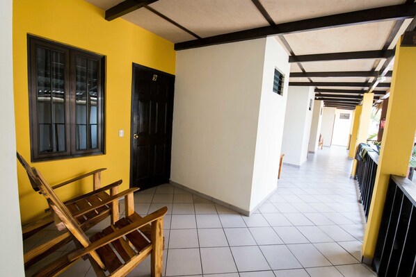 A hallway with a wooden bench, a black door, and a yellow wall.