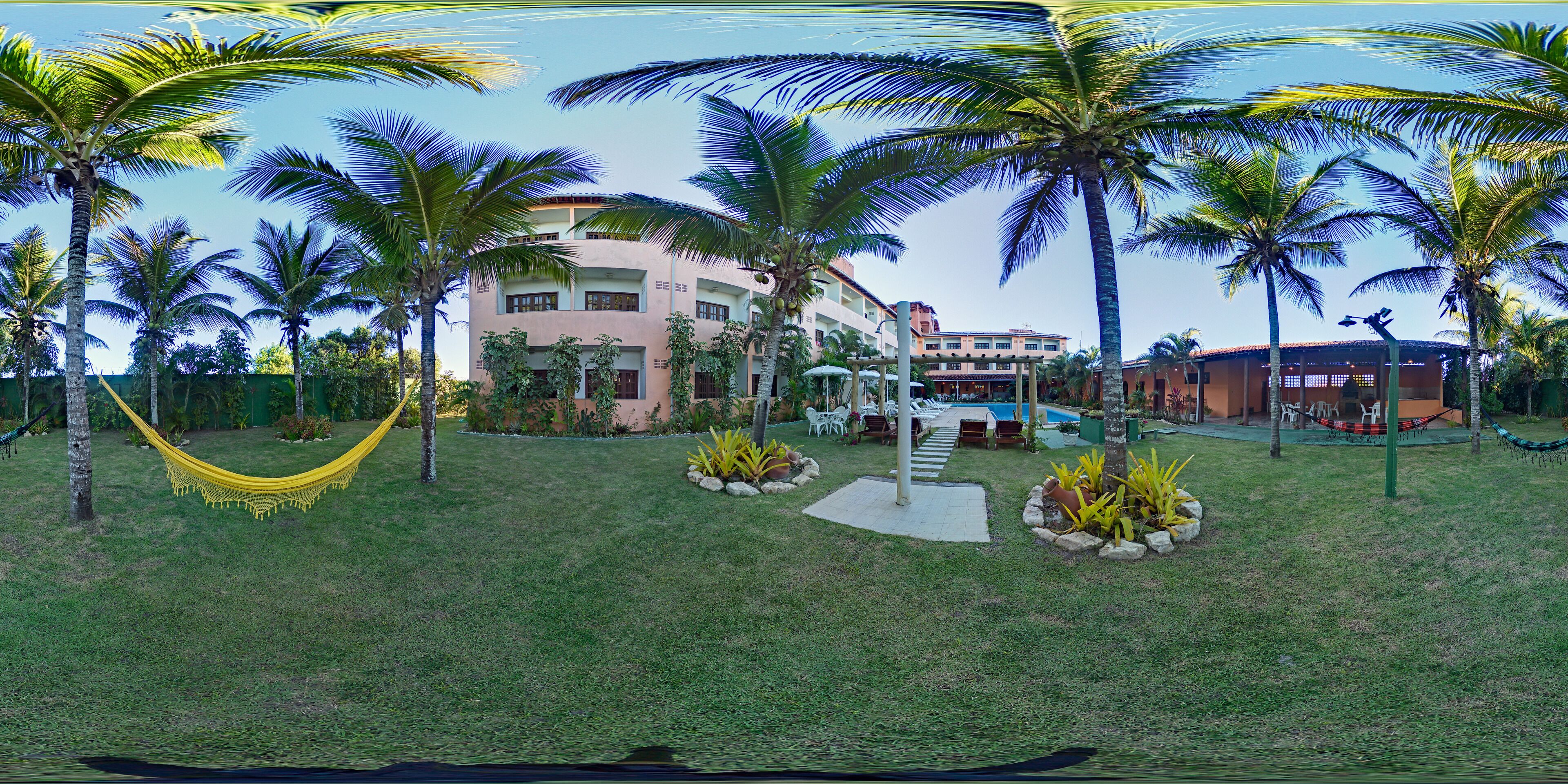 A resort with a pool, palm trees, and a hammock.