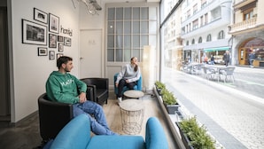 A modern interior with two sofas, a small round table, and a large window overlooking a street. - Koba Hostel (San Sebastián)
