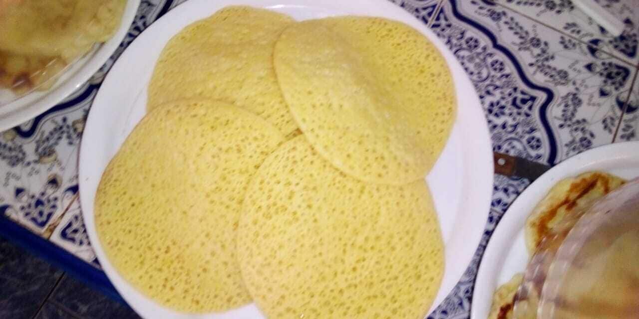 Ein Teller mit gelben Pfannkuchen auf einem Tisch, bedeckt mit einer blauen und weißen Tischdecke.