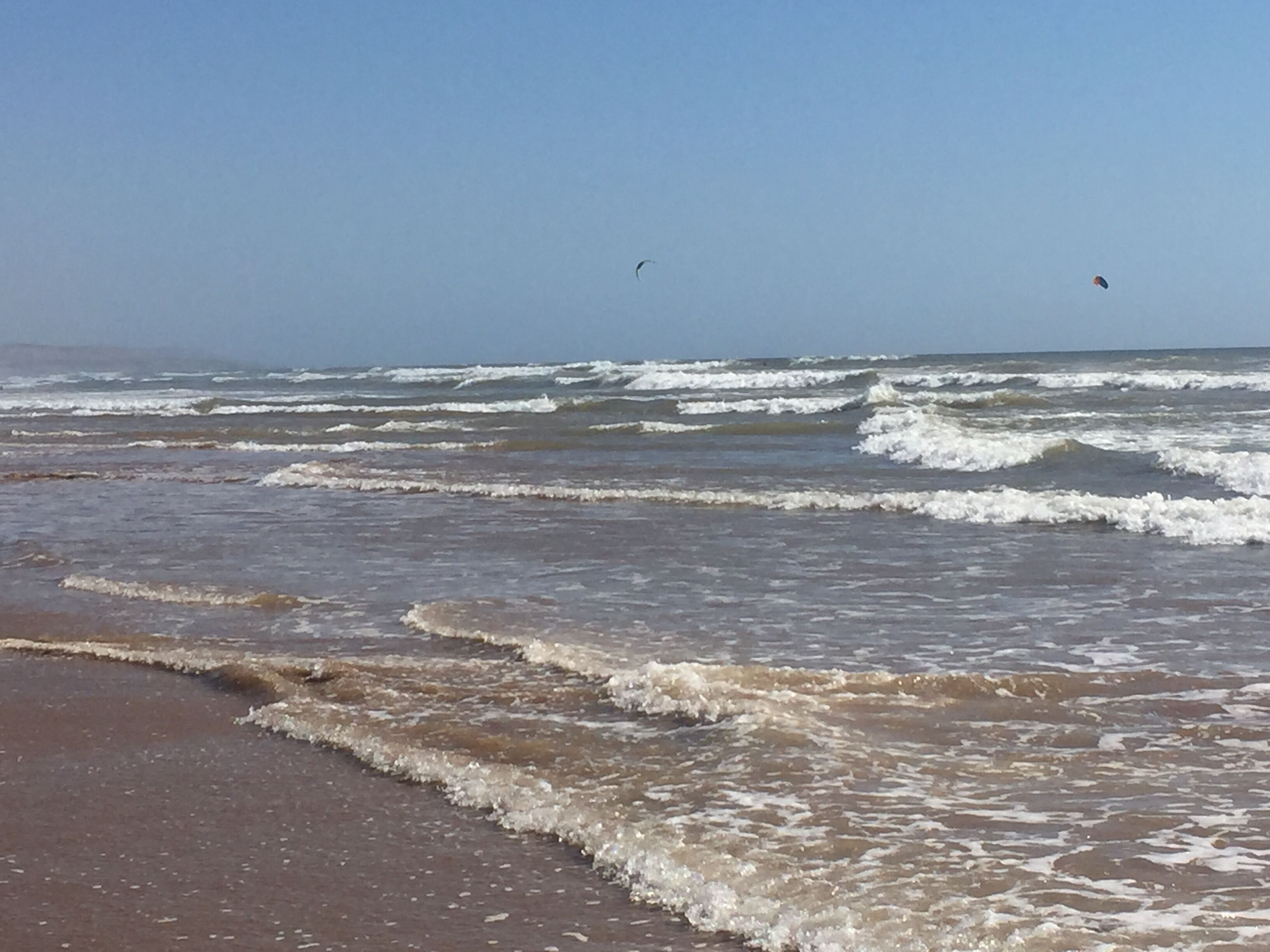 A beach with waves and a clear sky.