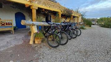 A rustic building with a stone facade, a wooden bench, and a row of bicycles parked in front.