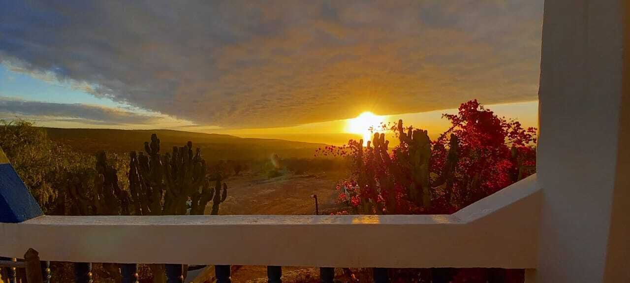 A balcony with a view of a sunset over a desert landscape.