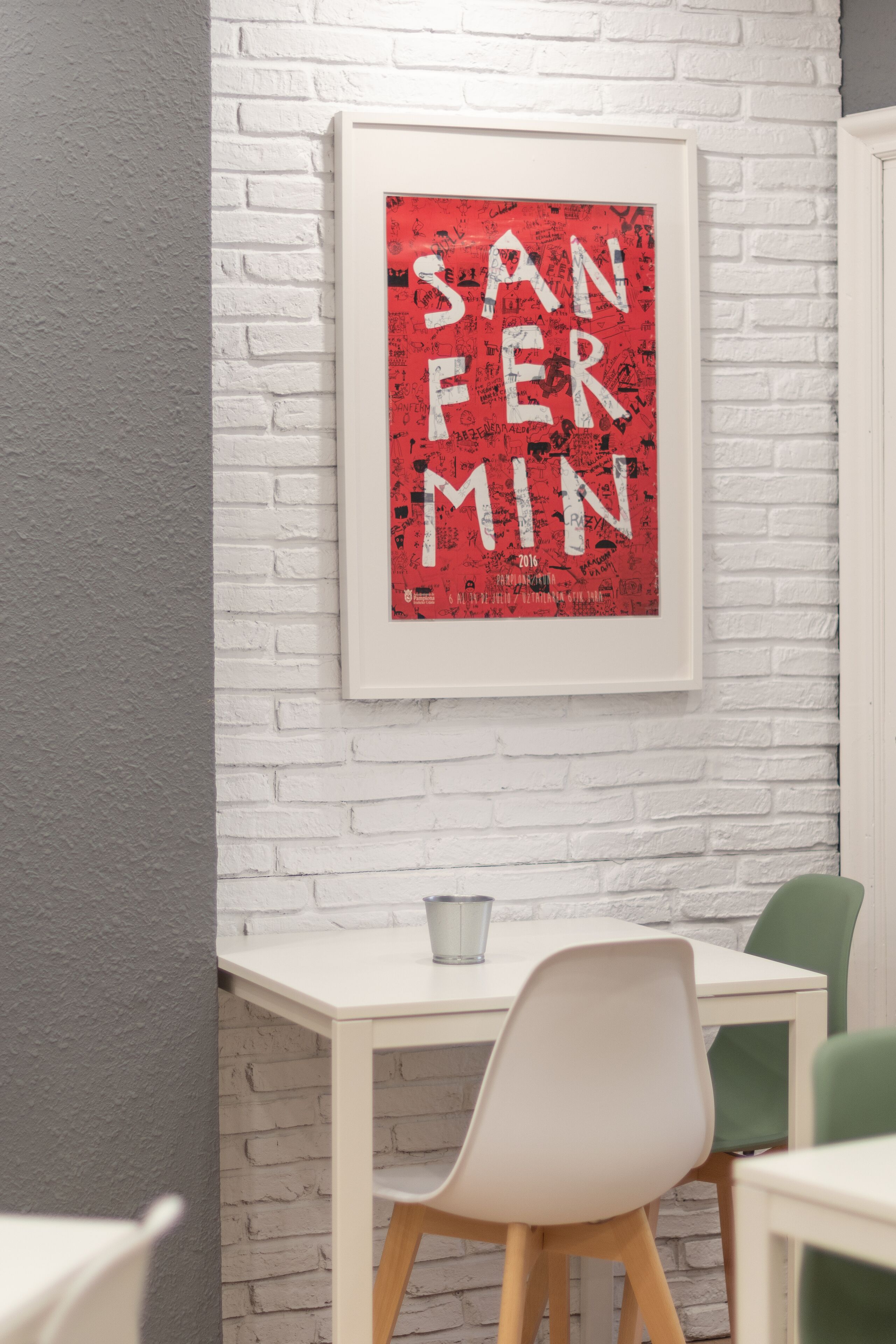 A framed artwork with the text "SAN FERN MIN" on a white brick wall.
