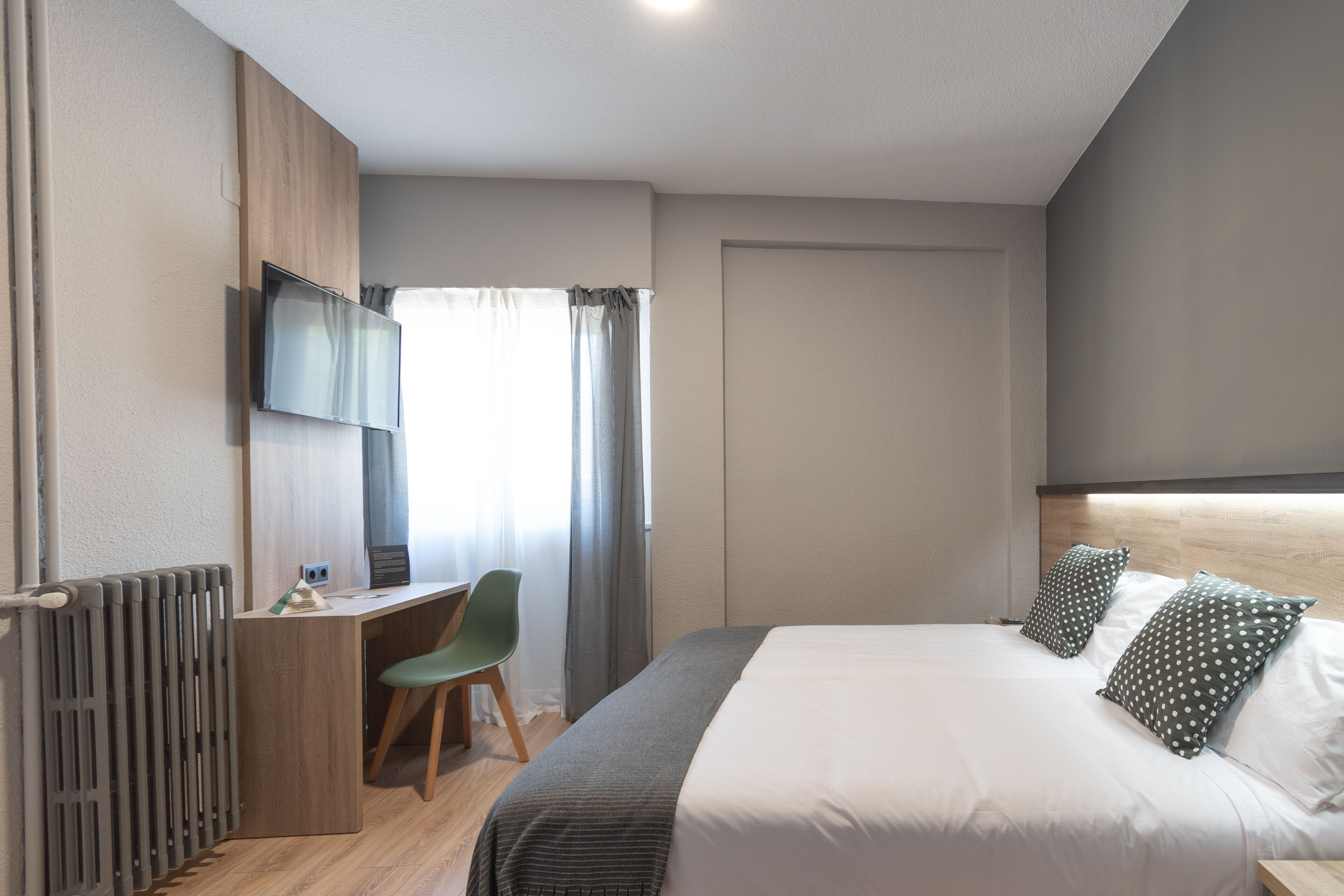 Una habitación de hotel moderna con cama, escritorio, silla y televisor.