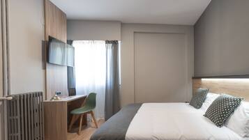 Una habitación de hotel moderna con cama, escritorio, silla y televisor.