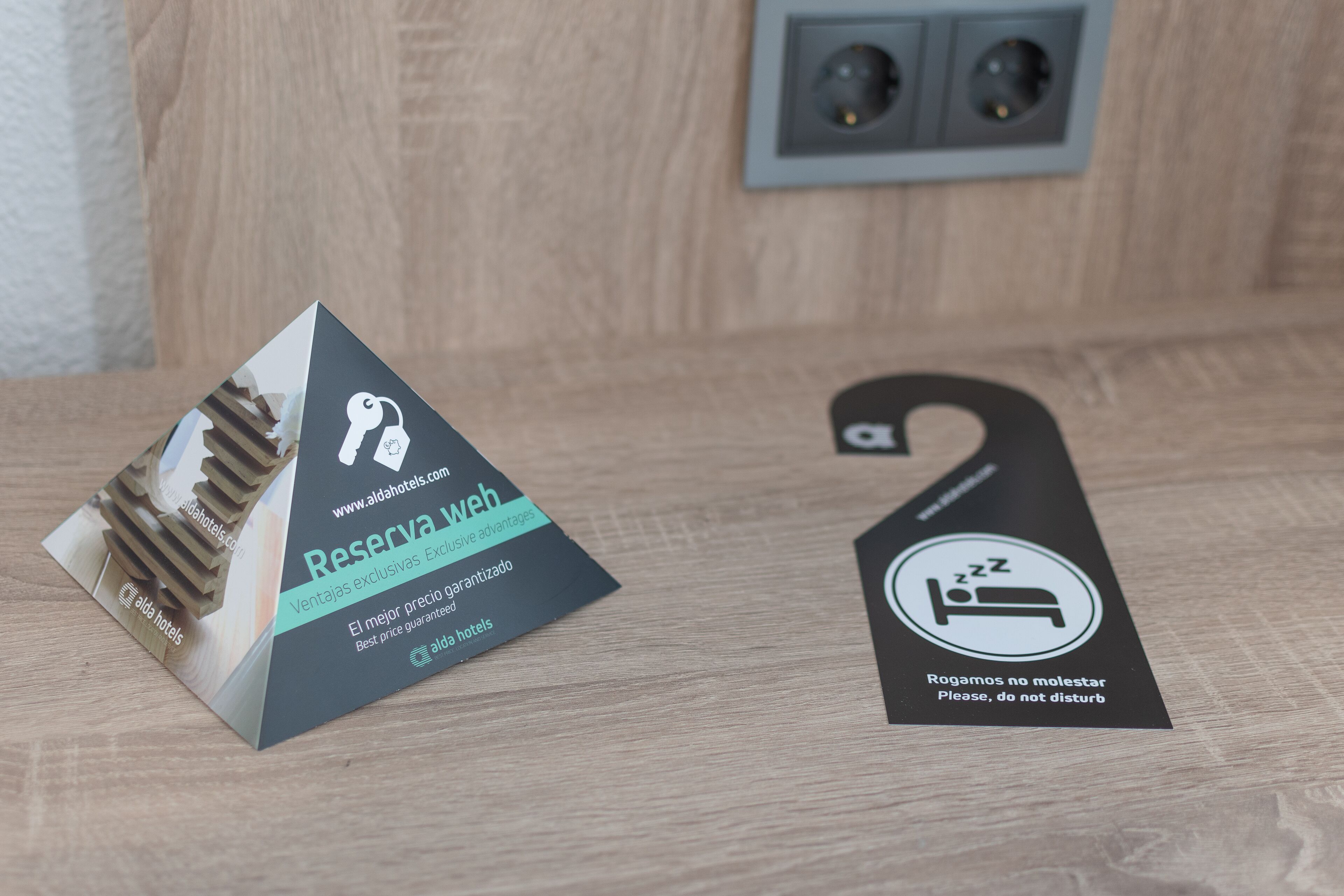 A hotel reservation card and a do not disturb sign on a wooden surface.