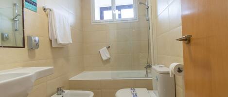 Un baño con bañera, dos lavamanos, inodoro y ducha.