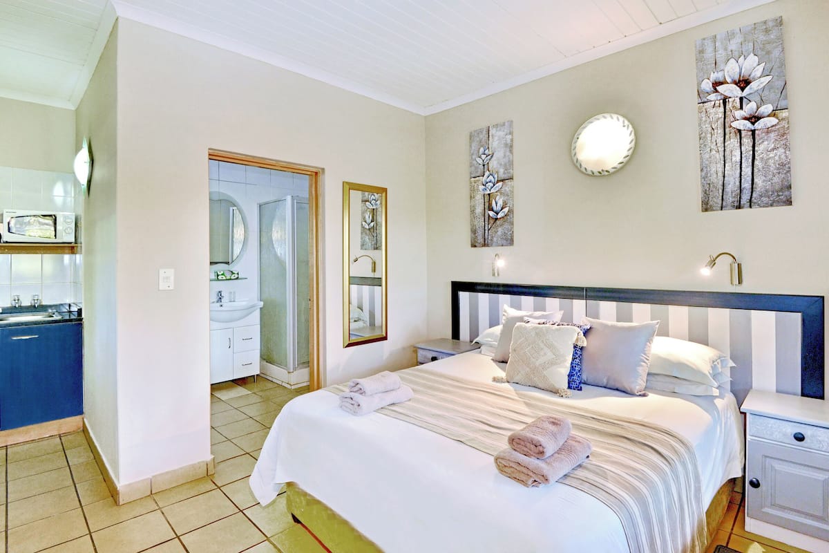 A bedroom with a bed, bedside tables, a nightstand, a mirror, and artwork on the walls.