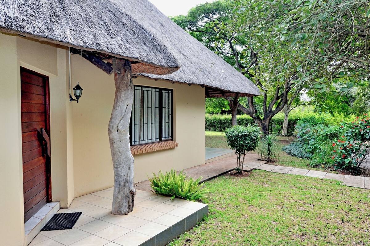 A house with a thatched roof, a wooden door, and a window with bars.