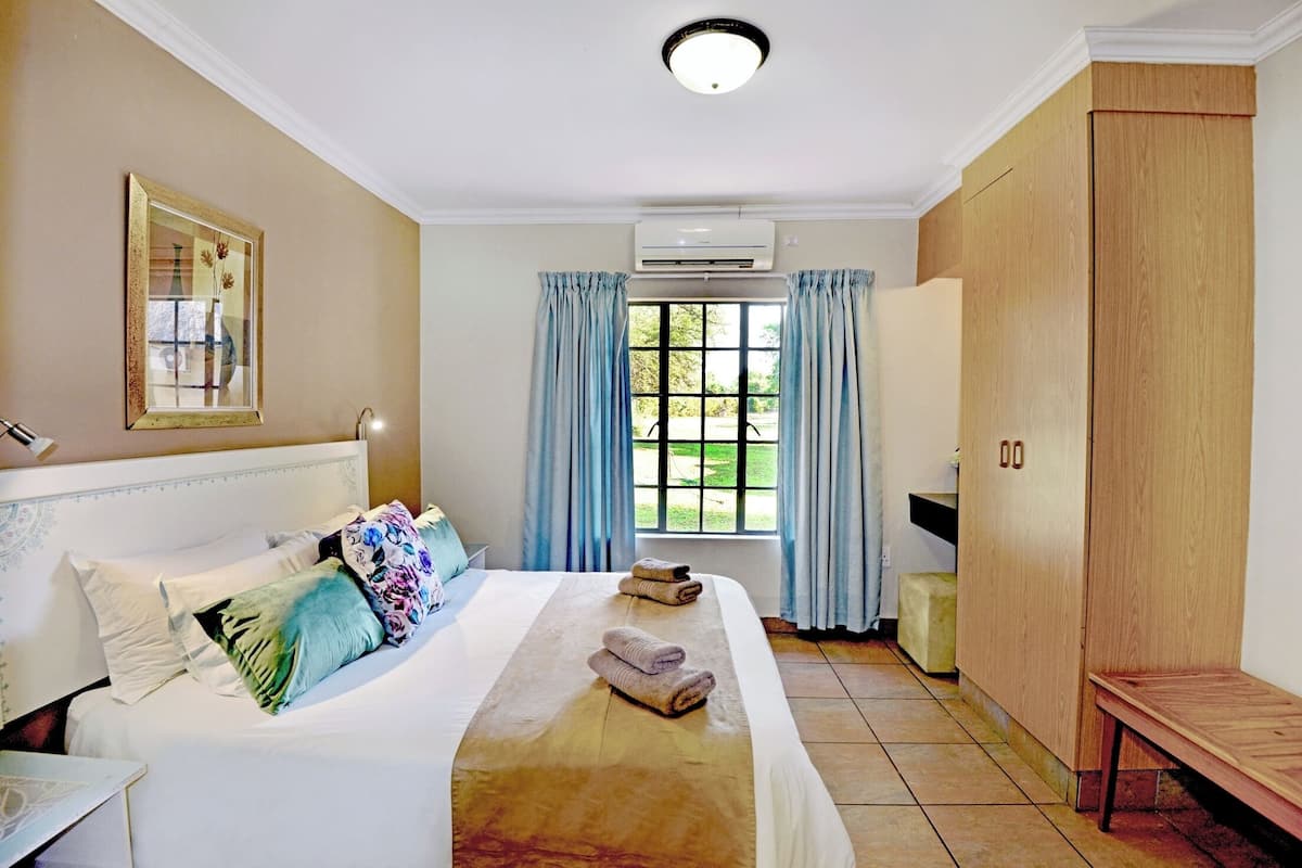 A hotel room with a bed, a bedside table, a wardrobe, and a window with curtains.