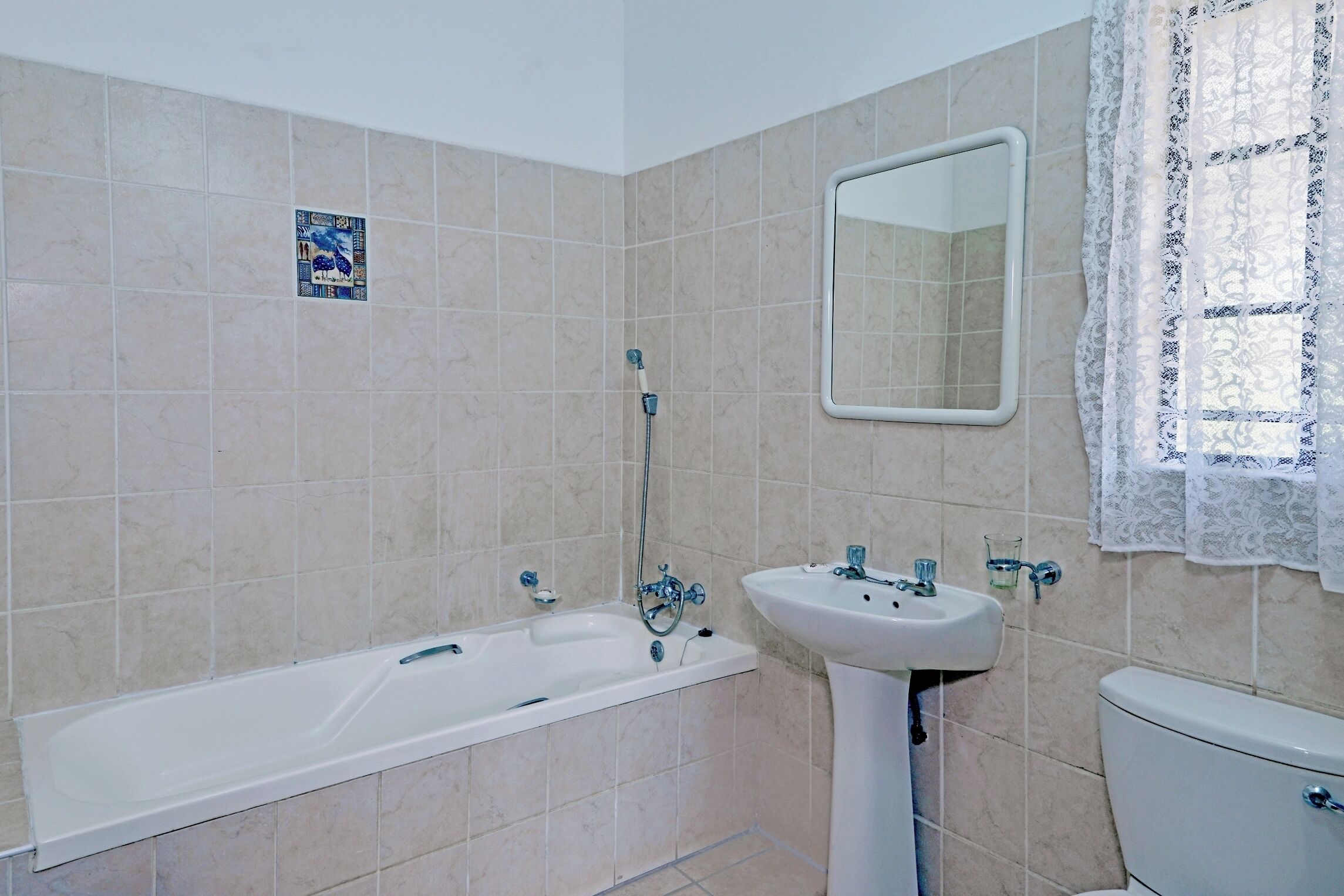 Un baño con bañera, lavamanos, inodoro y espejo.