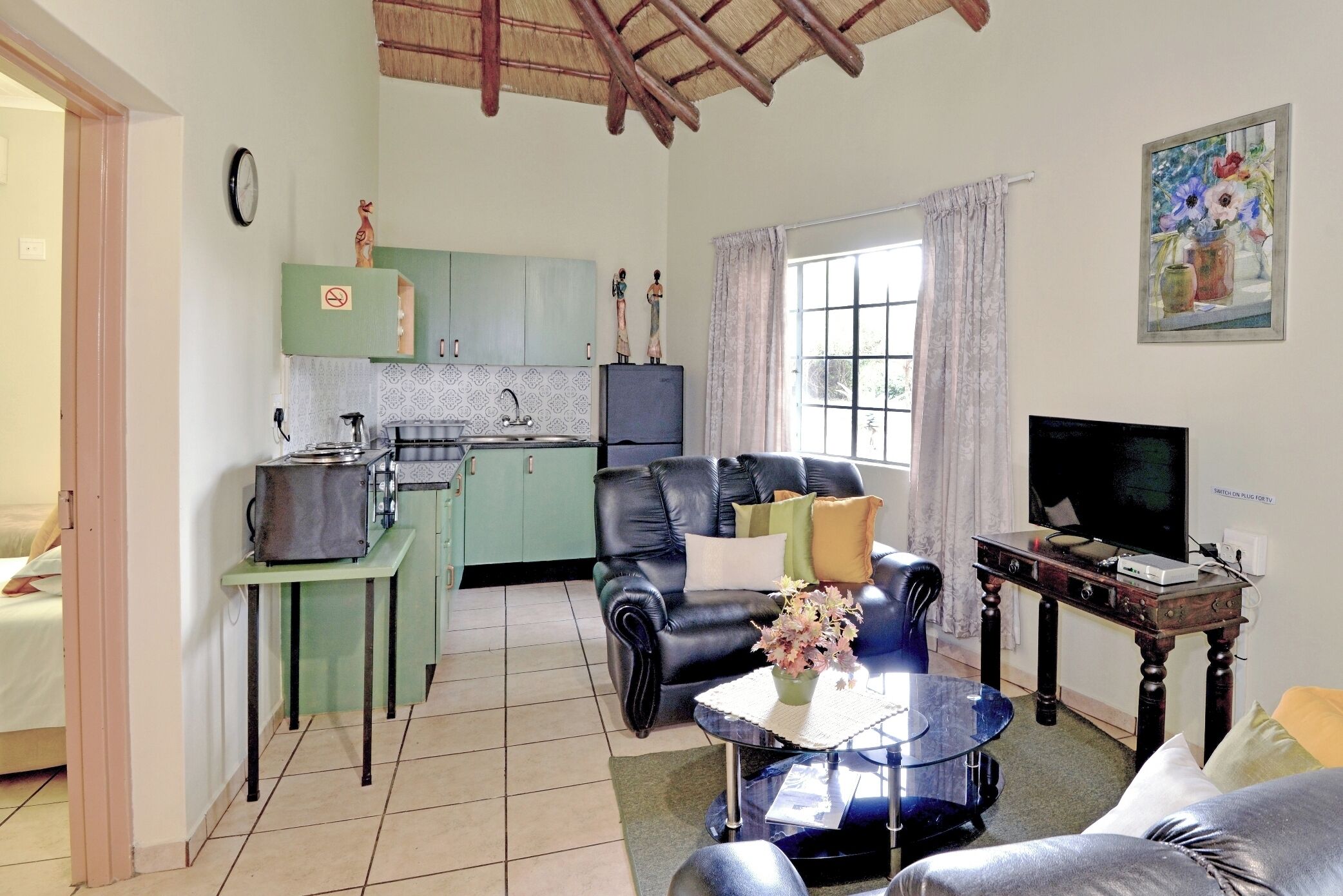 A compact living space with a kitchenette, a dining area, and a seating area with a TV.