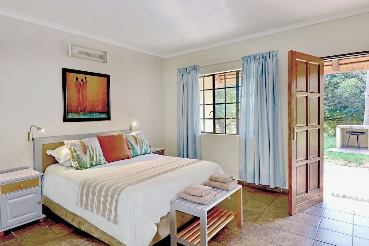 A bedroom with a bed, bedside table, and a window with curtains.