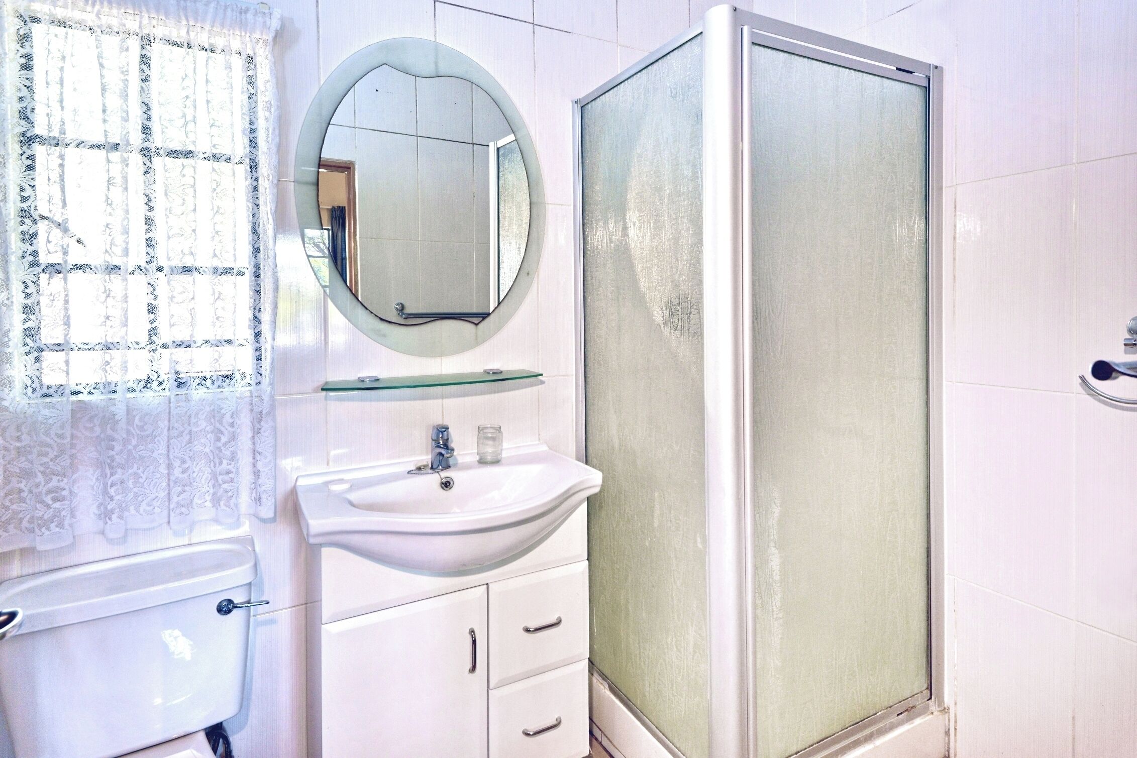 Ein Badezimmer mit Toilette, Waschbecken, Spiegel und Duschkabine.