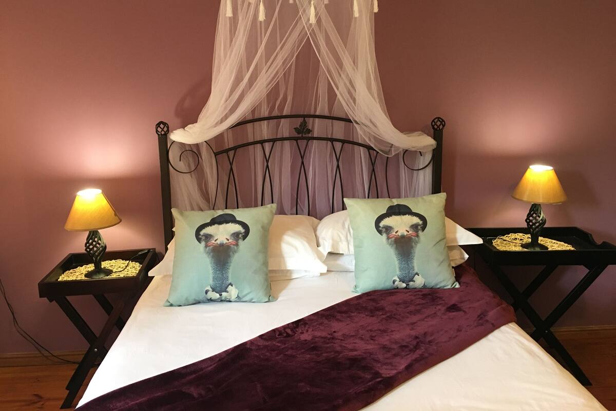 A bed with a canopy, two bedside lamps, and two decorative pillows with animal faces.