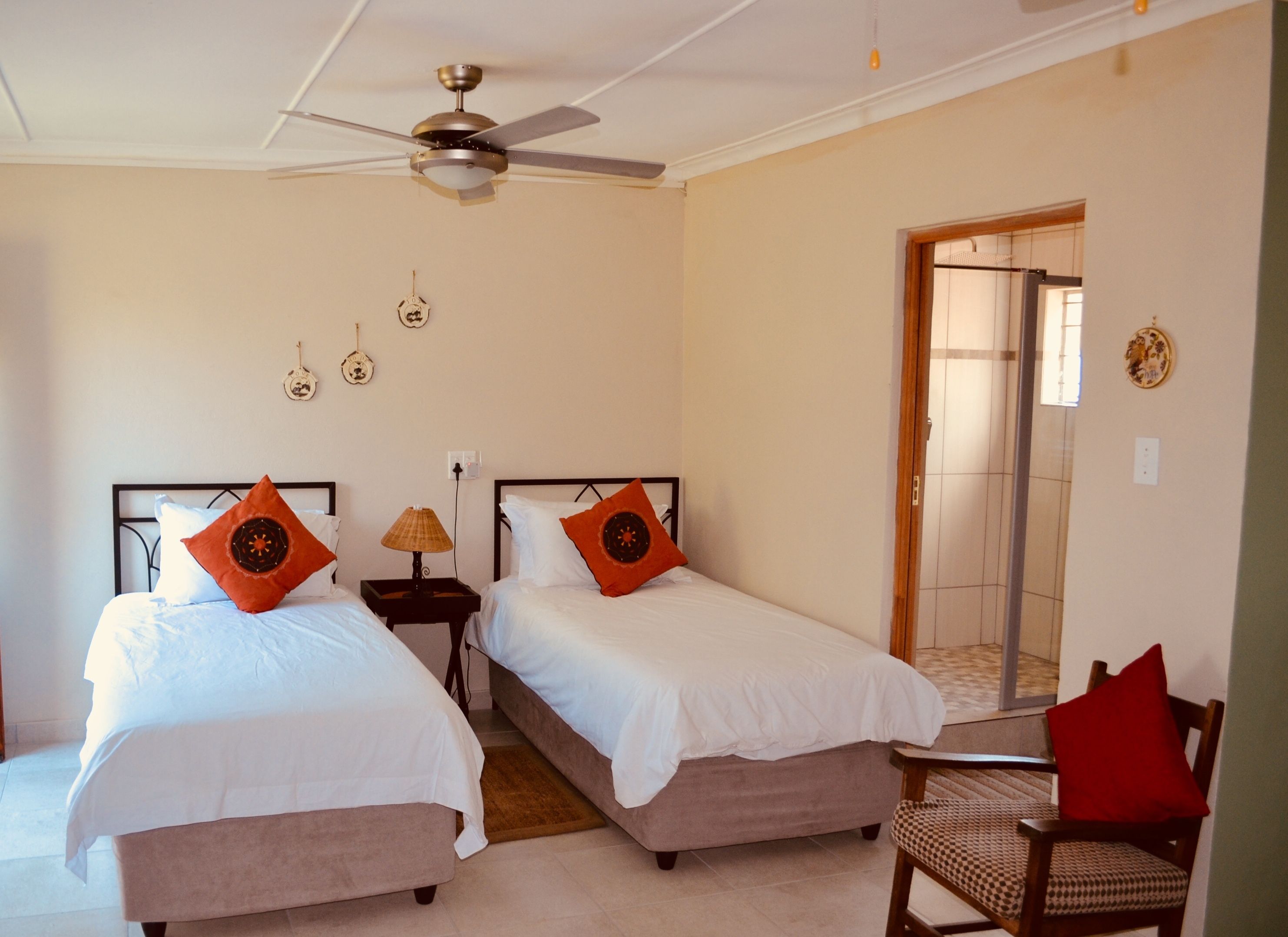 Une chambre d’hôtel avec deux lits, un ventilateur de plafond, une lampe, une chaise et un miroir.