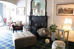 A cozy living room with a fireplace, a comfortable armchair, a plaid floor, and a potted plant. - New Park Hotel Athenry (Athenry)