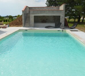 Une piscine rectangulaire, avec une structure en pierre en arrière-plan.