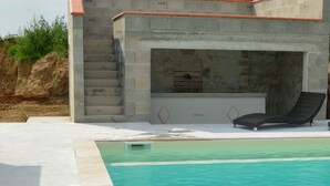 Une piscine avec un mur en pierre et un fauteuil de relaxation.